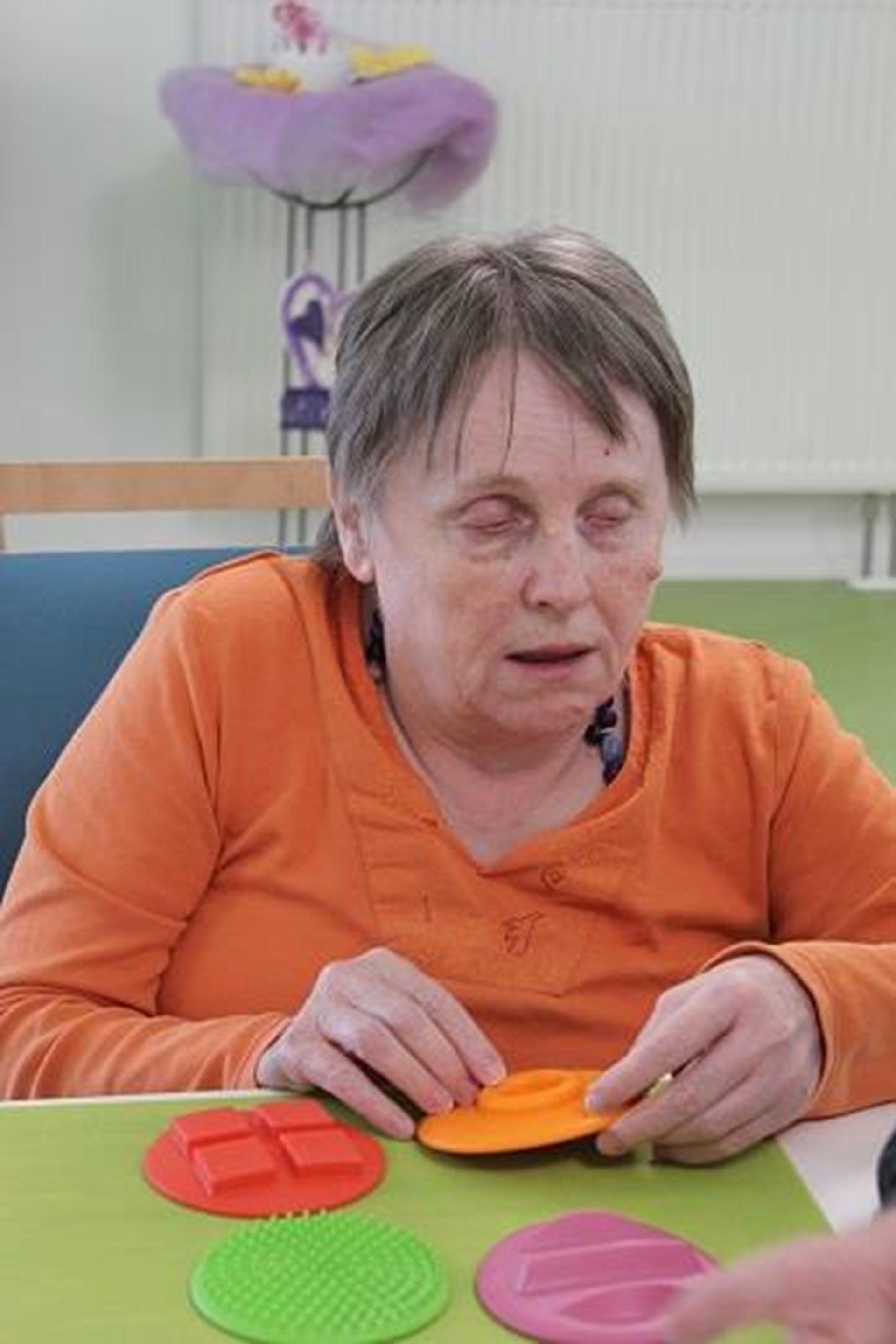 Eine Frau sitzt am Tisch und dühlt unterschiedliche Formen.