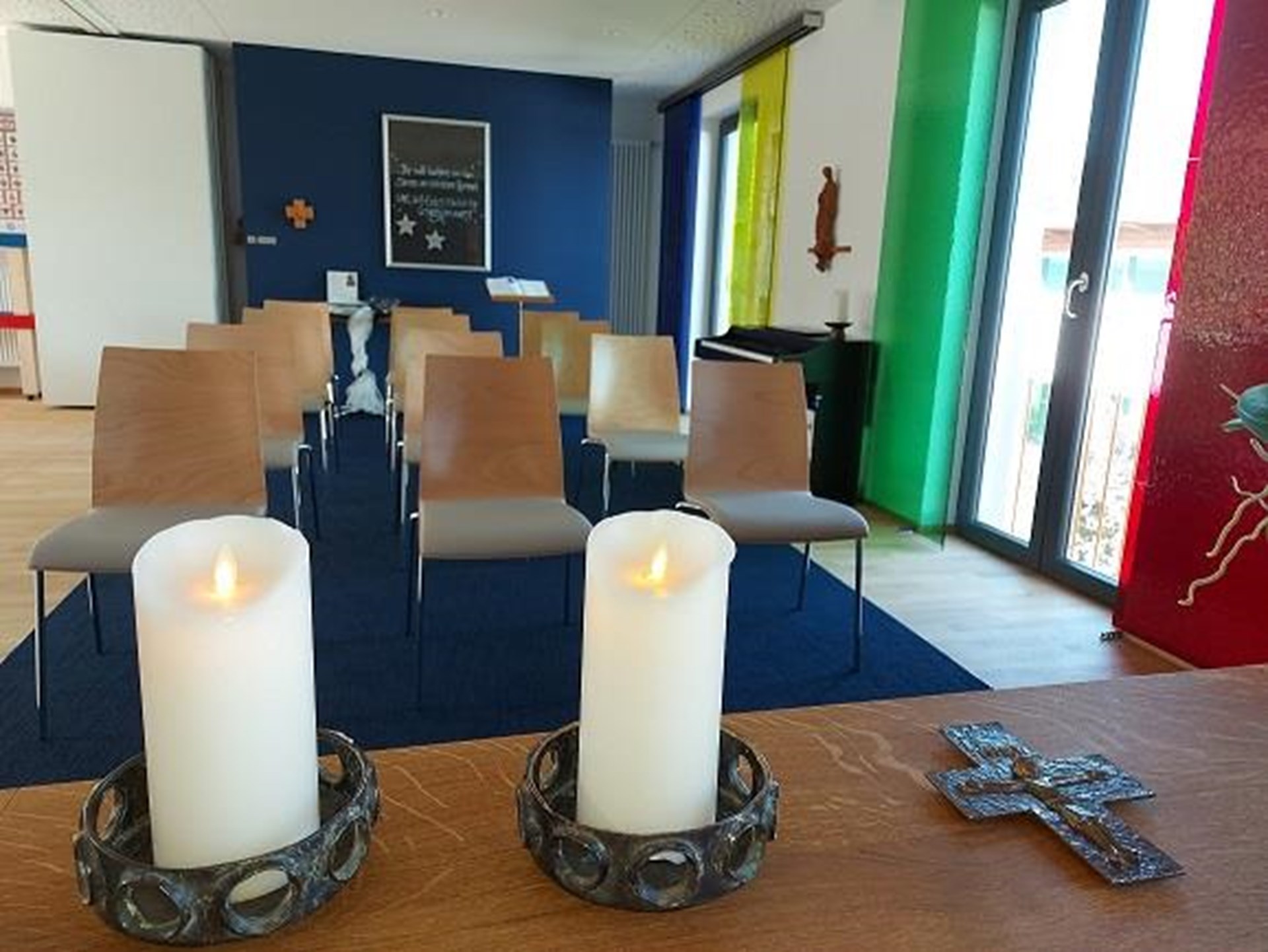 Wir blicken über brennende Kerzen auf dem Altar in den Besucherraum der Kapelle